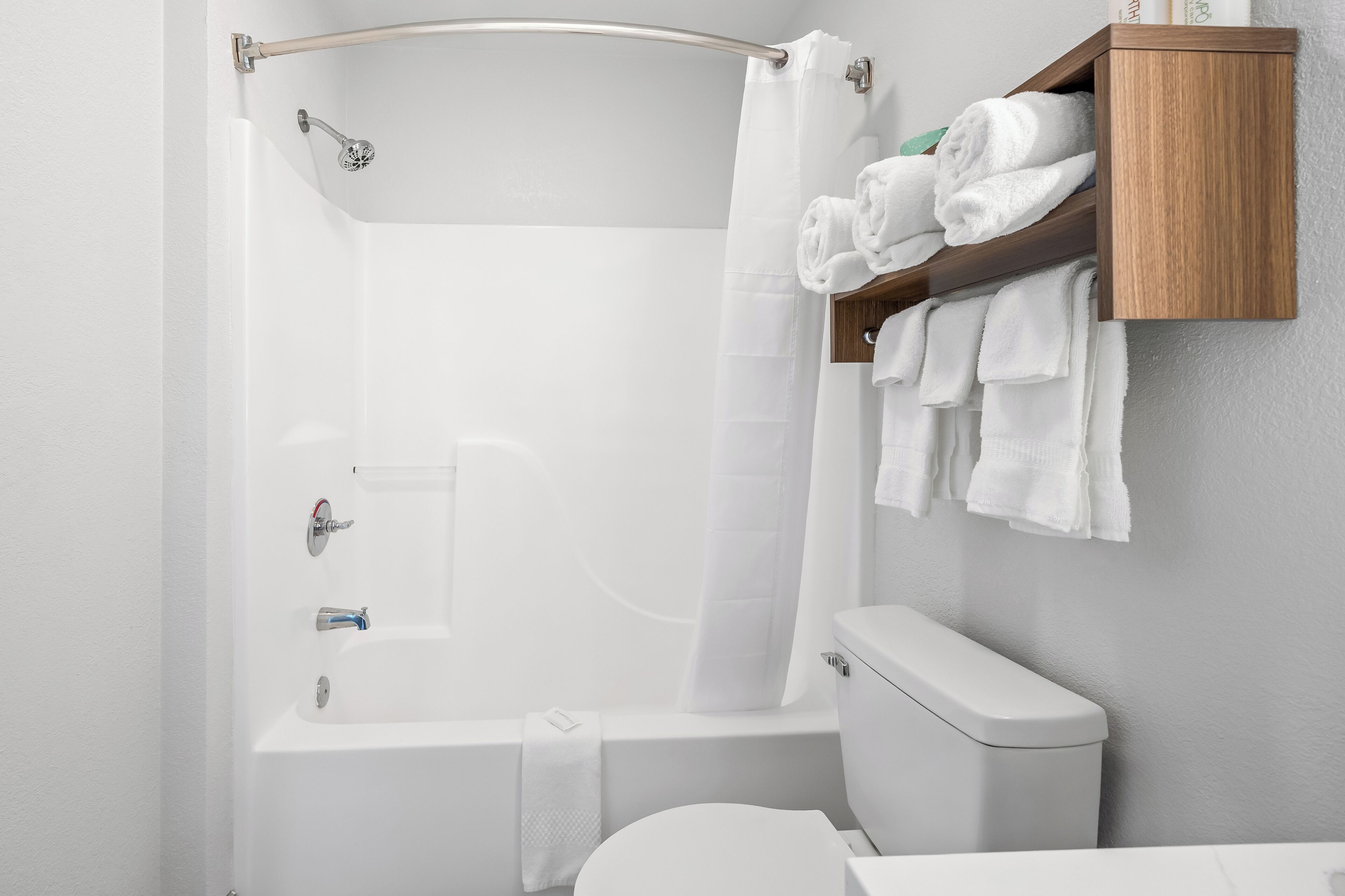A bathroom with a bathtub, toilet, and a wooden towel rack.