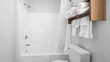 A bathroom with a bathtub, toilet, and a wooden towel rack.