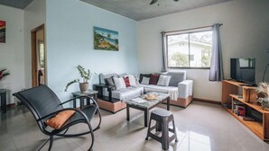 A living room with a sofa, coffee table, chairs, a ceiling fan, a TV, and a window with curtains. - Mahali 2: House with 2 bedrooms in Puerto Viejo (Puerto Viejo de Talamanca)