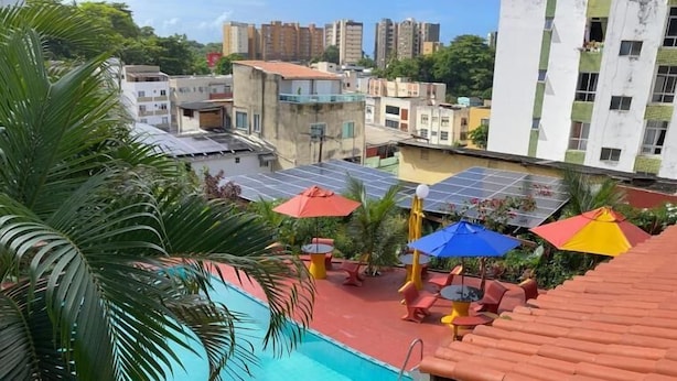 A rooftop pool with a blue pool, red roof, and outdoor seating with umbrellas. - Point PRV (Salvador)