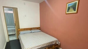 A room with a bed, a door, a wall-mounted picture, and a ceiling light. - Point PRV (Salvador)