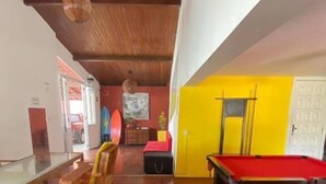 A room with a pool table, wooden chairs, a dining table, and a red sofa. - Point PRV (Salvador)