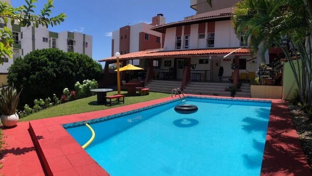 A swimming pool with a red border, a yellow umbrella, and a small inflatable ring. - Point PRV (Salvador)