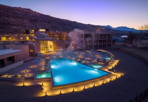 Ett hotell med pool, solstolar och en imponerande bergskedja i bakgrunden.