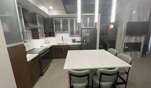 Une cuisine moderne dotée d’un îlot central, d’appareils électroménagers intégrés et d’un coin repas avec des chaises.