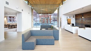 En modern hotellobby med en stor sittgrupp, en receptionsdisk och utsikt över omgivningarna.