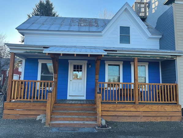 A two-story house with a porch, wooden steps, and a front door. - Cozy Trailside Getaway. Snowmobile and ATV Trail Access. Near Sugarloaf. (Eustis)