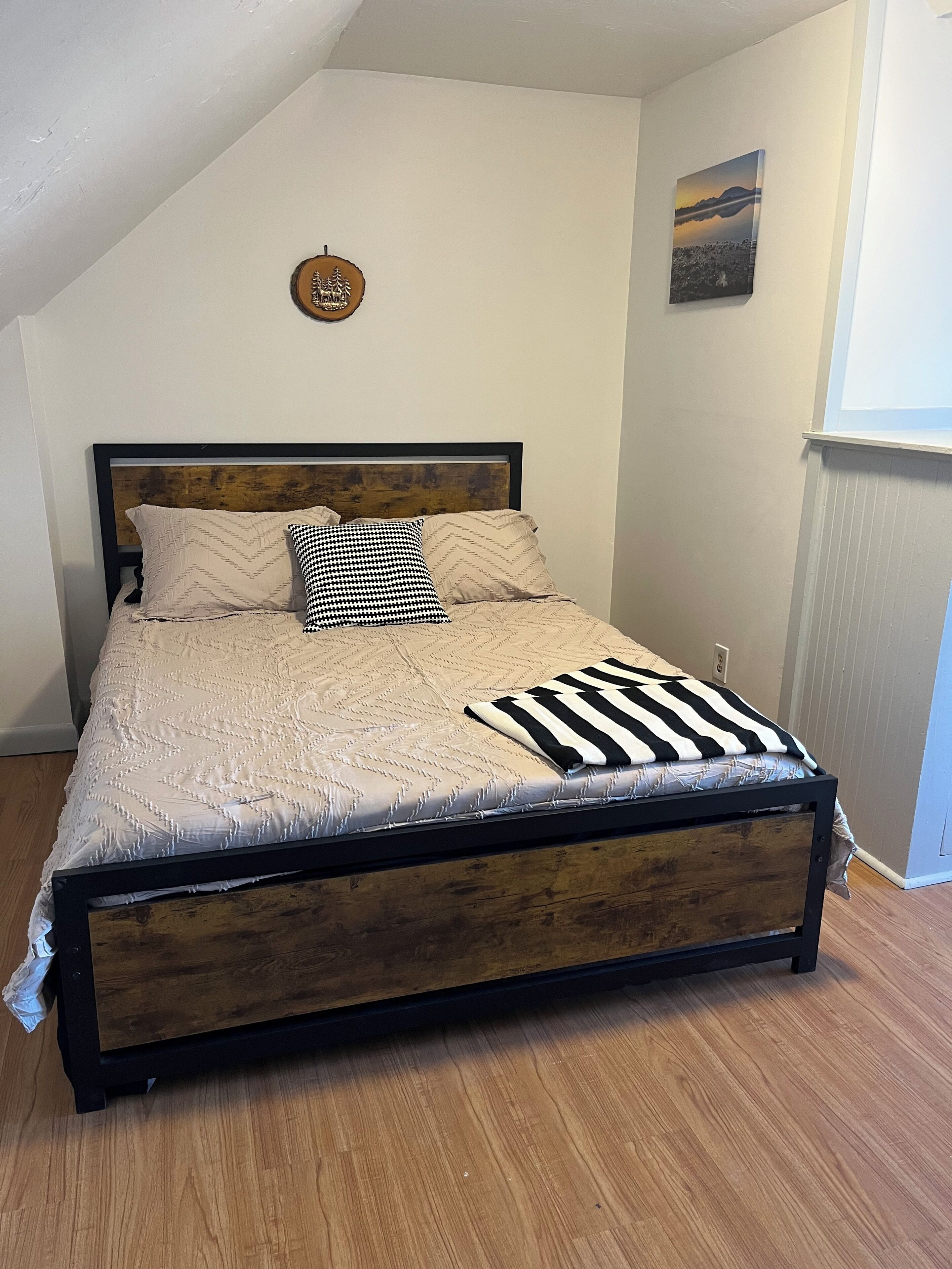 Een bed met een houten frame, een sprei en twee kussens.