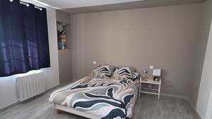 Ein Schlafzimmer mit einem Bett, einem Nachttisch, einem Heizkörper und einem Fenster mit Vorhängen.