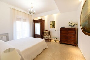 Un dormitorio con una cama grande, un aparador de madera, una silla y una mesita.