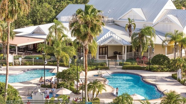 A resort with multiple swimming pools, palm trees, and a covered patio area. - Orlando | Couples Theme Park Getaway | Pool + Hot Tub (Orlando)
