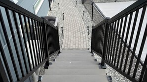A staircase leading to a residential area with houses, trees, and a clear view of distant mountains.