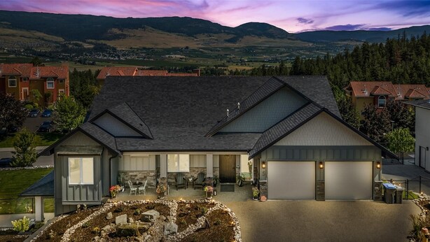 A two-story house with a large garage, a stone fireplace, and a landscaped garden.