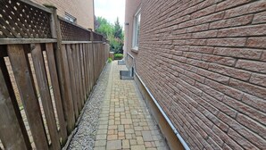 A narrow brick pathway flanked by a wooden fence and a brick wall.