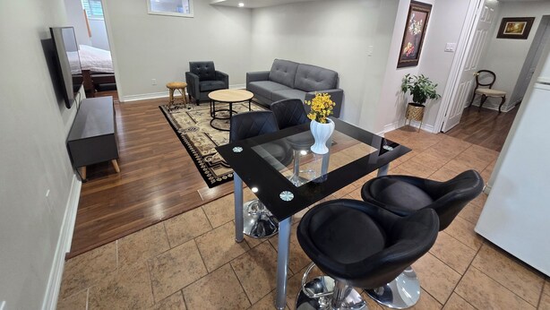 A modern living room with a sofa, armchairs, a coffee table, and a dining area with chairs.