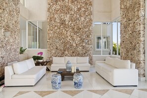 Un salon spacieux avec un ensemble de canapés blancs, une table basse et des vases décoratifs.