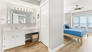 A bedroom with a bed, a vanity with a mirror, and a ceiling fan. - Coastal Shores - Direct Oceanfront w/ Pool in North Myrtle Beach (North Myrtle Beach)