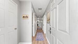 A hallway with white doors, a wooden floor, and a blue rug. - Coastal Shores - Direct Oceanfront w/ Pool in North Myrtle Beach (North Myrtle Beach)