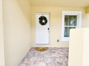 A door with a wreath, a window, and a stone-tiled entrance.