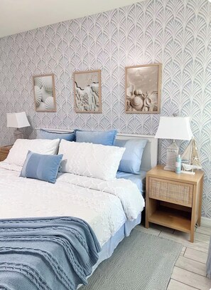 A bedroom with a bed, nightstands, and wall art.