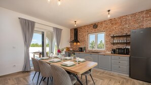 Una cucina moderna con una parete in mattoni, pavimento in legno e zona pranzo con tavolo apparecchiato per quattro.