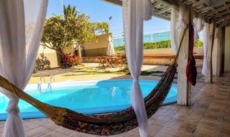 Área de piscina com rede, móveis de exterior e vista para a paisagem circundante.