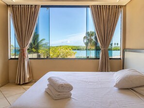 A hotel room with a bed, a view of the sea, and curtains. - Casa da Lagoa - Marechal Deodoro-AL  (Marechal Deodoro)