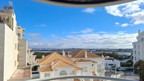 A residential area with buildings, a clear sky, and a distant view of a bridge. - PRAIA DA ROCHA - DOM QUIXOTE (Portimão)
