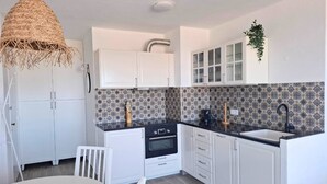 Una cocina compacta con armarios blancos, encimera negra y salpicadero estampado.