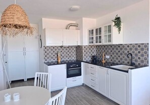 A compact kitchen with white cabinets, a black countertop, and a patterned backsplash. - PRAIA DA ROCHA - GREEN TOWER 18 (Portimão)