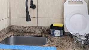 Eine Küche mit integriertem Spülbecken, einer Kaffeemaschine, einem Reiskocher und einem Geschirrständer.