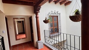 A covered balcony with terracotta tiles, a metal railing, and hanging planters. - Terrace with volcano view/ Colonial Villa + Parking in Antigua Guatemala (Antigua Guatemala)