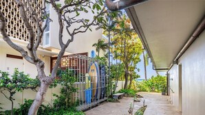 A covered outdoor area with a pathway, a gate, and a surfboard rack. - OCEANSIDE SANCTUARY - Waterfront 2 bed/2bath on Oahu's Gold Coast (Honolulu)
