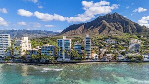 A coastal cityscape with modern buildings, a mountain in the background, and clear turquoise waters. - OCEANSIDE SANCTUARY - Waterfront 2 bed/2bath on Oahu's Gold Coast (Honolulu)