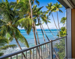 A balcony with a view of the ocean and palm trees. - OCEANSIDE SANCTUARY - Waterfront 2 bed/2bath on Oahu's Gold Coast (Honolulu)