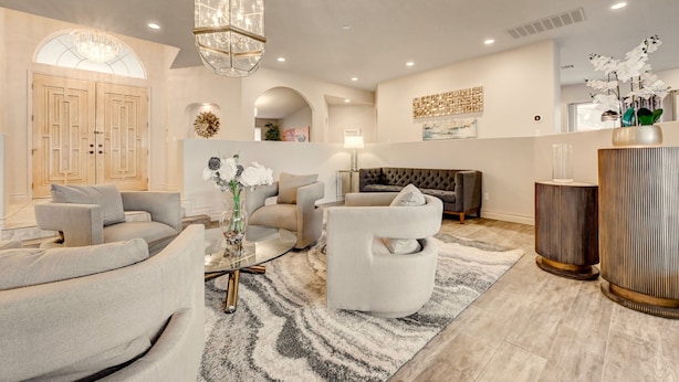 A modern living room with a sofa, armchairs, a coffee table, and a chandelier. - Quiet 4BR Home w/ Pool Near Summerlin and Strip Central to Everything (Las Vegas)