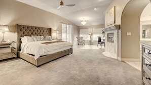 A spacious bedroom with a large bed, a fireplace, and a dining area. - Quiet 4BR Home w/ Pool Near Summerlin and Strip Central to Everything (Las Vegas)