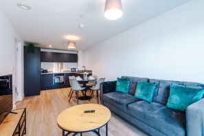 Ett modernt vardagsrum med en soffa, ett soffbord och en matplats med stolar och ett bord.