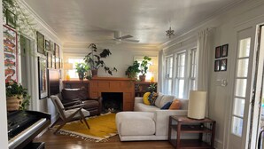 A living room with a fireplace, a piano, a sofa, and a coffee table. - Sunny, safe, walkable house with King bed and AC (Kansas City)