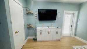 A room with a white cabinet, a TV mounted on the wall, a door, and a window. - BEACHHOUSE #1 Mermaids Paradise-full kitchen, private oceanfront patio 1st floor (Melbourne Beach)