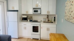 A compact kitchen with white cabinets, a microwave, a coffee maker, and a stove. - BEACHHOUSE #1 Mermaids Paradise-full kitchen, private oceanfront patio 1st floor (Melbourne Beach)