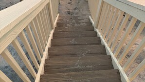 A wooden staircase leading to a beach with footprints in the sand. - BEACHHOUSE #1 Mermaids Paradise-full kitchen, private oceanfront patio 1st floor (Melbourne Beach)
