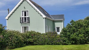 Ein zweistöckiges Haus mit Satteldach, einem Balkon und einem gepflegten Garten.