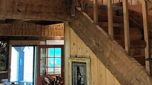 Ein Holzinnenraum mit Treppe, einer hängenden Blumenkomposition und gerahmten Bildern an den Wänden.
