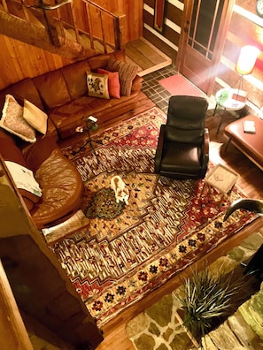 A cozy living room with a sofa, a chair, a patterned rug, and a staircase.