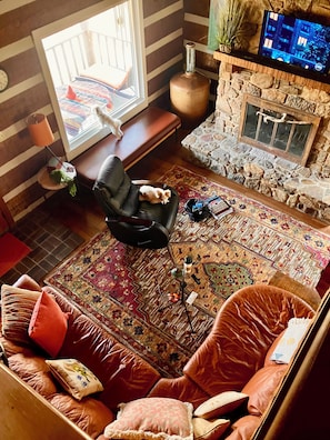 A cozy living room with a fireplace, a sofa, a chair, and a television.