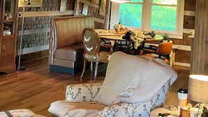 Ein rustikales Blockhaus-Interieur mit einer Erkerdecke, einem Essbereich und einer gemütlichen Sitzgruppe.