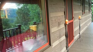 Eine Holzhütte mit großen Fenstern, einem Balkon und einer Veranda mit Kerzen.