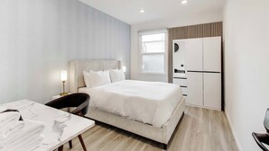 Una moderna camera d'hotel con un letto, un comodino, una lampada e vista sulla città attraverso la finestra.