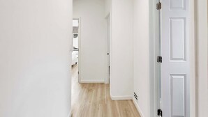 Un corridoio con pareti bianche, pavimento in legno e una porta bianca.